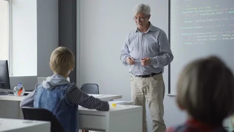 Calm aged teacher asking students learning computer programming Stock Footage 142491869