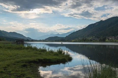 Calm alpine lake with sky reflection at the sunset. Stock Photos