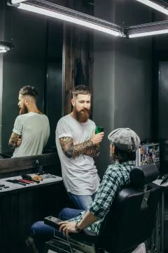 Calm barber looking at his client while standing Stock Photos