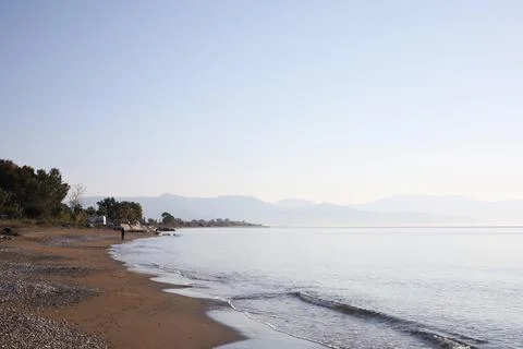 Calm beach with distant mountains Stock Photos