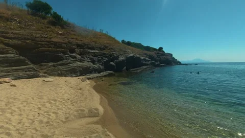 Calm beach meets clear blue water under bright sun. Trani Ammouda, Greece Stock Footage 339613573