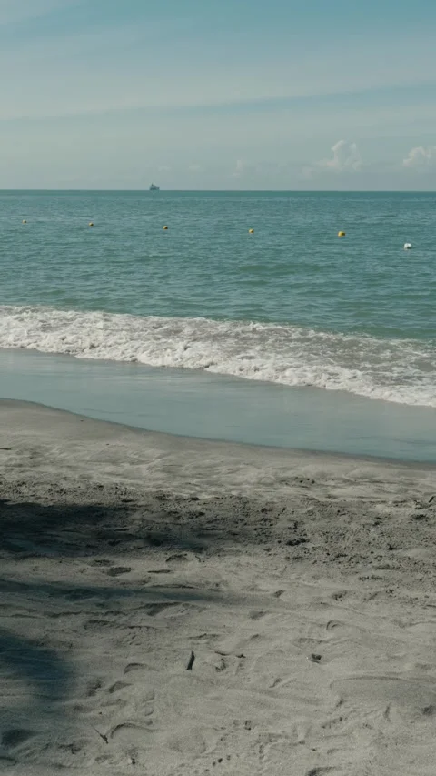 Calm Beach Scene with Gentle Waves, Buoy Line, and Distant Boat Stock Footage 322721745
