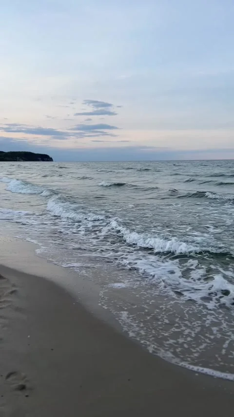 Calm beach shoreline with gentle waves and foamy surf under a pastel sky. Stock Footage 335451616