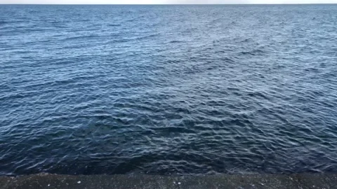 Calm black sea, with a slightly cloudy blue sky, shot from the beach Stock Footage 201973002