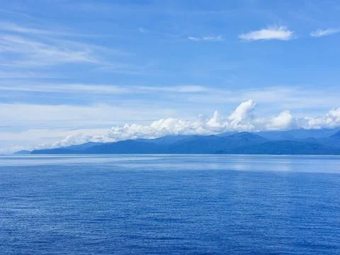 Calm Blue Ocean Horizon with Distant Island Mountains. Stock Photos