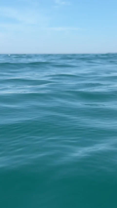 Calm blue sea surface with small gentle waves under a clear sky and distant hori Stock Footage 342140148