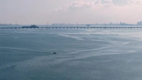 Calm blue sea water with distant bridge and hazy industrial skyline Stock Footage 339841806