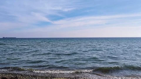 Calm Blue Sea Waves On Pebble Beach With Ship On Horizon Under Sunny Sky Video stock 337587174