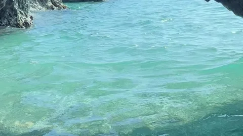 Calm Blue Waters Gently Lap Against Rocky Shores in a Serene Coastal Cove During Stock Footage 318387083