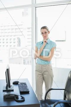 Calm businesswoman standing thoughtful in her office Stock Photos