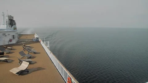 Calm cruise ship deck with empty lounge chairs overlooking a vast, foggy ocean Stock-Footage 288168583