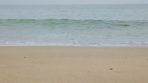 Calm emerald green ocean waves rippling onto a clean sandy beach Stock Footage 338194037