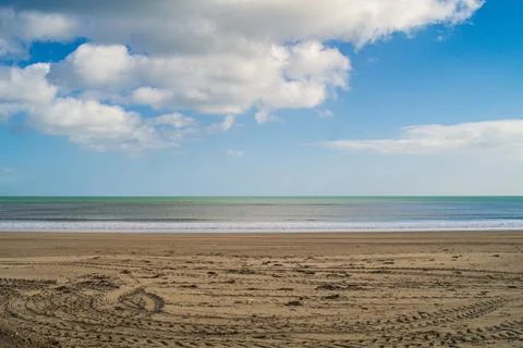 Calm empty sandy beach and sea horizon under blue sky with clouds Stock Photos