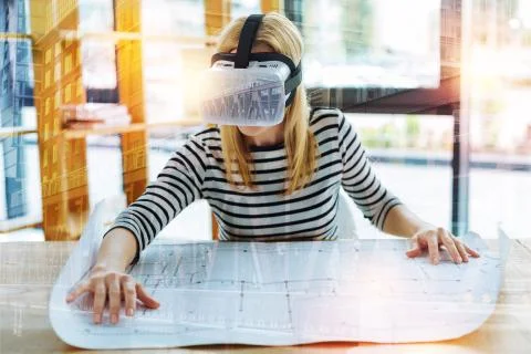 Calm engineer wearing virtual reality glasses and working with a drawing Foto stock