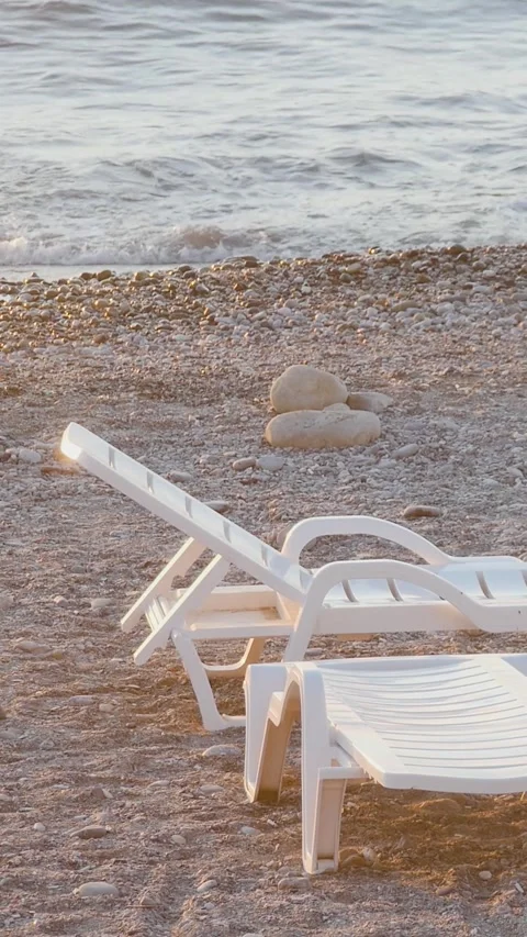 Calm evening at the seaside with sun flare hitting plastic beach beds on a g Stock Footage 334627681
