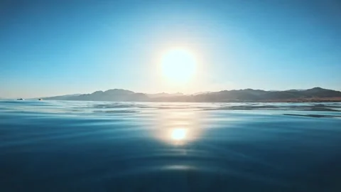 Calm hypnotic sea water surface with sunlight reflection and distant coast with Видео 323935752