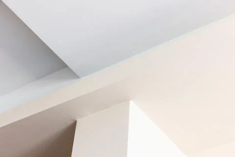 A calm interior scene featuring intersecting white and beige walls with sha.. 스톡 사진