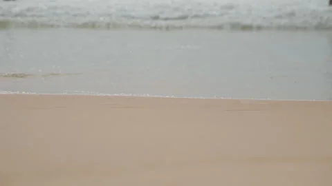 Calm island shoreline featuring soft surf and distant swimmers. Relaxing Stock Footage 335167963