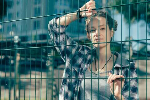 Calm lady looking confident while touching the chain link fence Stock Photos