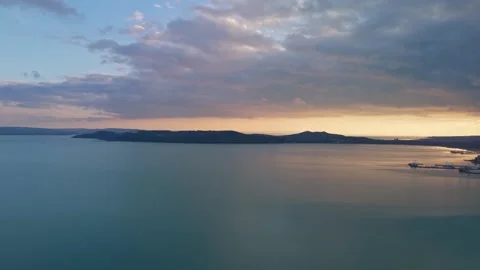 Calm Lake Balaton reflects a cloudy sunset from a drone view near Tihany Stock Footage 336467319