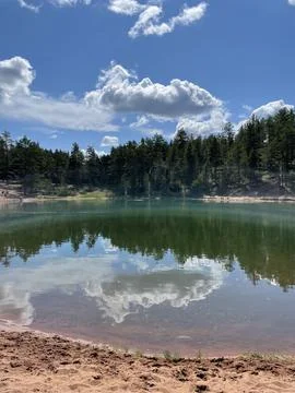 Calm Lake with Cloud Reflections and Forest Shoreline Stock Photos