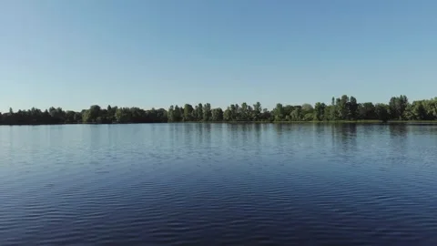 Calm Lake Surface Reflecting Clear Blue Sky With Distant Forest Horizon Line Video stock 342231291