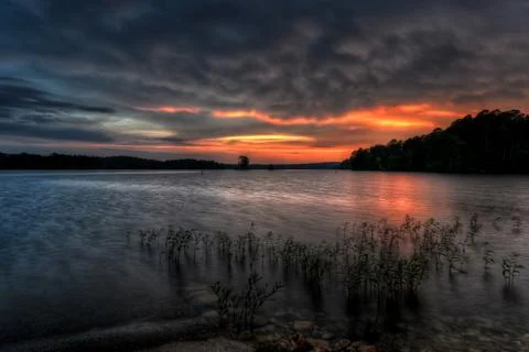 Calm Lakefront at Sunset With Dramatic Clouds Stock Photos