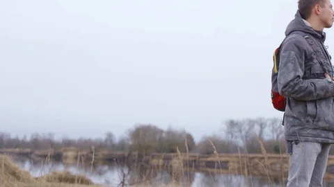 Calm man with backpack standing on hill and looking into distance Stock Footage 128572832