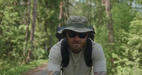 Calm man cycling through forest, front camera tracking Stock Footage 312354909