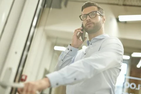 Calm man talking on the phone while entering the room Stock Photos