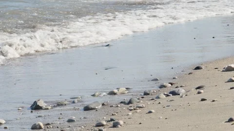 Calm Mediterranean sea waves breaking on a pebbly beach during a sunny day. Stockbeeldmateriaal 333663123