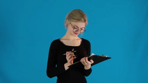 Calm model with makeup writes on paper holding clipboard Stock Footage 306474053