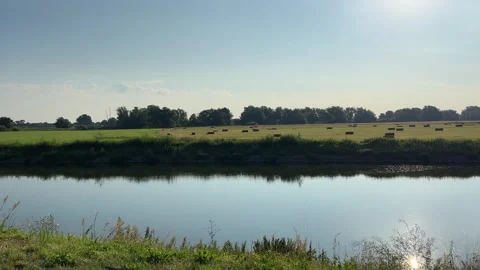 Calm Morning River with Mooring Post and Rectangular Hay Bales, 4K Stock Footage 339700728
