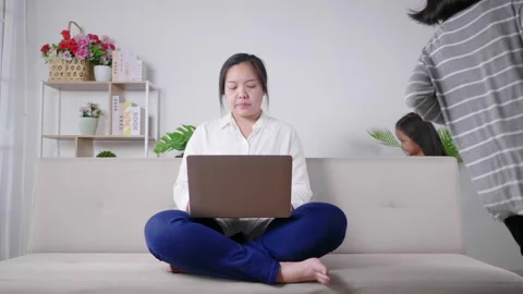 Calm mother sit on couch working on laptop, little kids play around Video stock 163779318