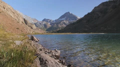 Calm mountain lake, focus on some rocks in foreground Stock Footage 146028659