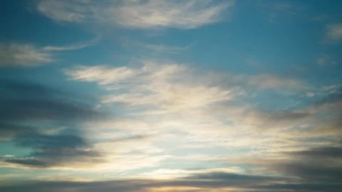 The calm movement of fluffy white clouds across the blue sky at sunset. Vídeo Stock 332475949