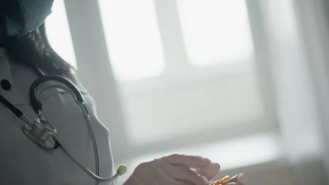 Calm nurse readies tiny vial. Dedicated healthcare professional with protective Stock-Footage 346556993