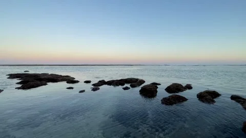 Calm Ocean and Dark Rocks Under Pastel Sky in Bali Stock Footage 337354504
