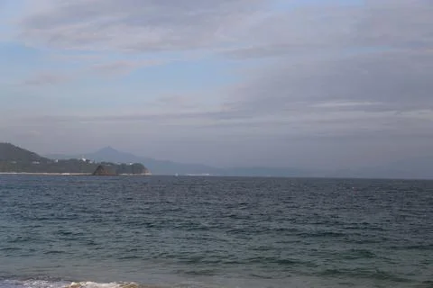 A calm ocean with a cloudy sky in the background Stock Photos