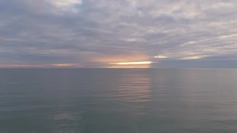Calm ocean horizon at sunset with clouds reflecting on water Stock Footage 328281963