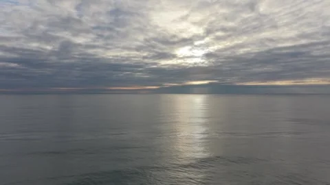 Calm ocean horizon at sunset with clouds reflecting on water Stock Footage 328282043