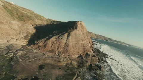 Calm ocean meets rugged cliffs under soft sunlight Stock Footage 341826390