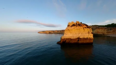 Calm ocean meets rugged cliffs under fading sun Video stock 346091586