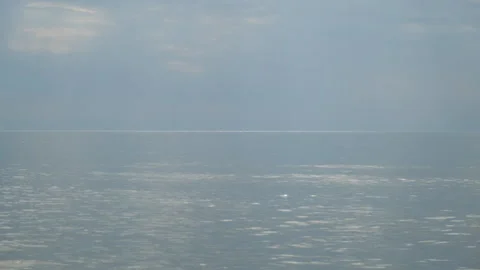 Calm ocean reflecting sunlight under cloudy sky at sunset in evening. Video stock 311473150