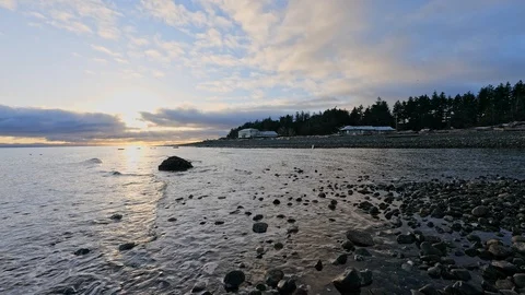 Calm ocean at sunrise with small waves and homes in the distance. Stock Footage 129001646