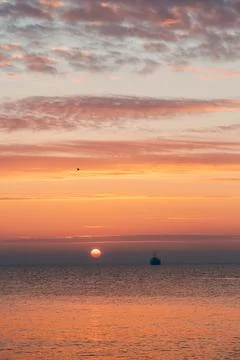 Calm Ocean Sunset With Distant Ship Silhouette and Scenic Sky Cloudscape Photos