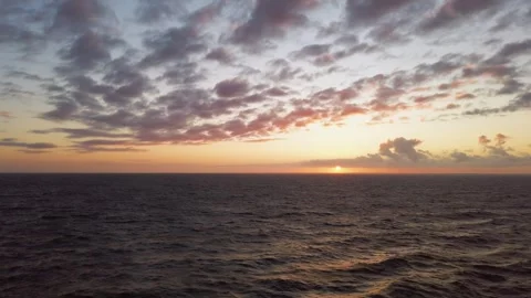 Calm ocean at sunset, with rays of sun peeking through clouds near horizon. Stock Footage 293134550