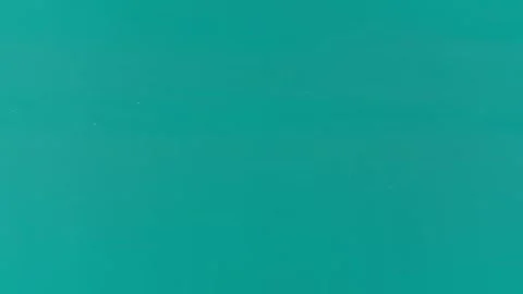 Calm ocean surface with gentle waves rolling toward a distant shore under a clea Stock Footage 338001915