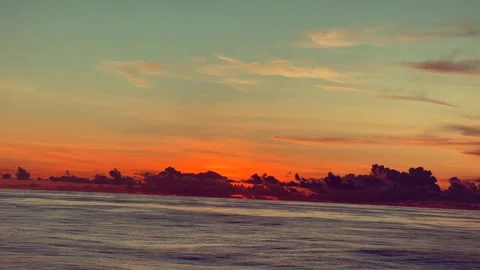 Calm ocean surface under a vibrant sunset sky with colorful clouds on the h.. Stock Footage 338281731