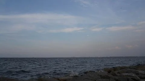 Calm Ocean View at Dusk with Cloudy Sky and Distant City Stock-Fotos